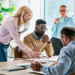 Four people work at a table, coordinating their MLS partnerships.